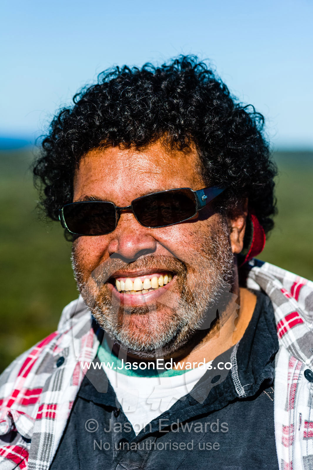 A smiling Aboriginal man wearing sunglasses on a bright sunny day. Blue Lake National Park, Queensland, Australia.