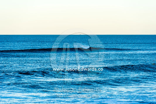 A clean wave peels toward the beach at twilight. Queensland, Australia.