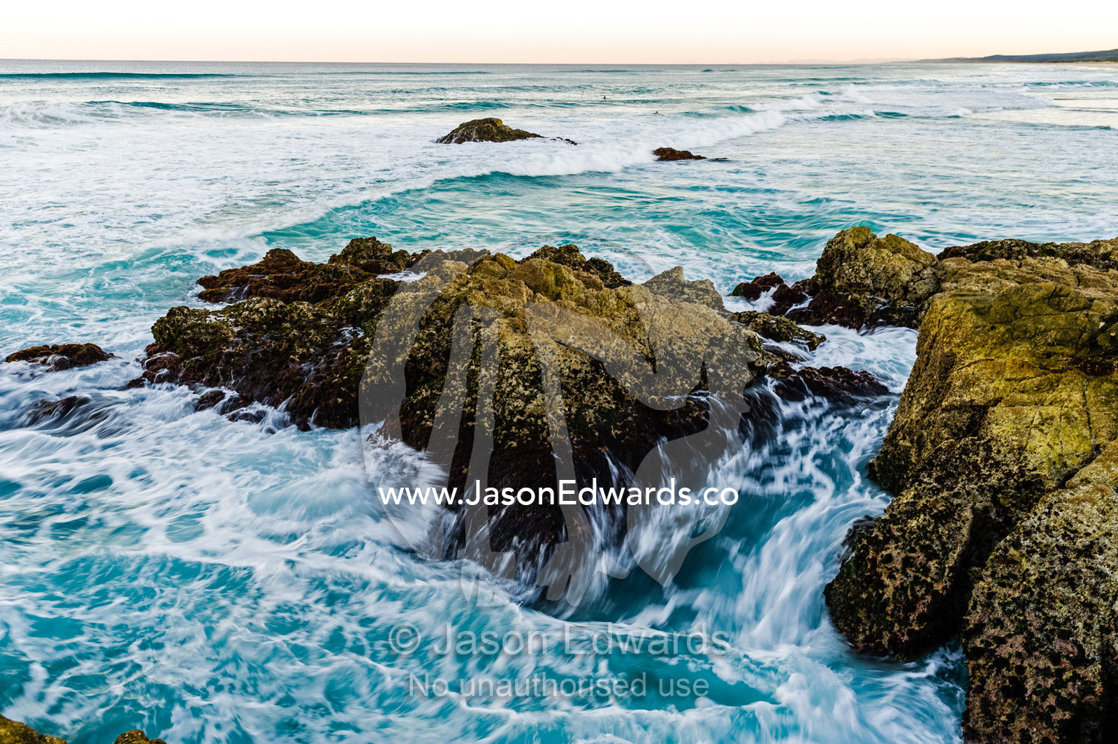 Waves smash against jagged rocks on a pristine coastline. Queensland, Australia.