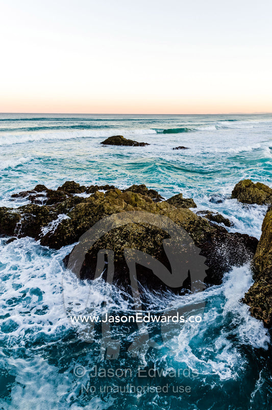 Waves smash against jagged rocks on a pristine coastline. Queensland, Australia.