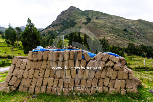 A farmhouse being constructed with handmade mud bricks in the Andes mountains. Pisac, Peru.