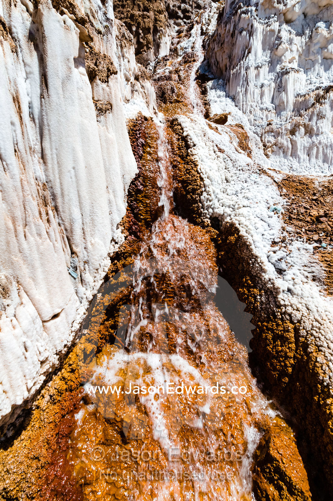 Salty spring water flows down channels into terraced evaporation ponds in an Inca salt mine. Maras, Peru.