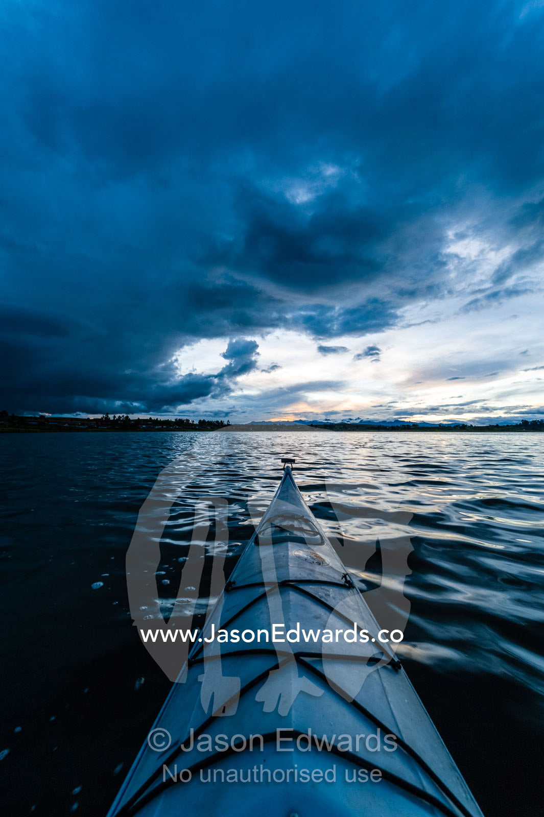 A canoe bow on a still lake in the Andes mountains beneath storm clouds. Peru.