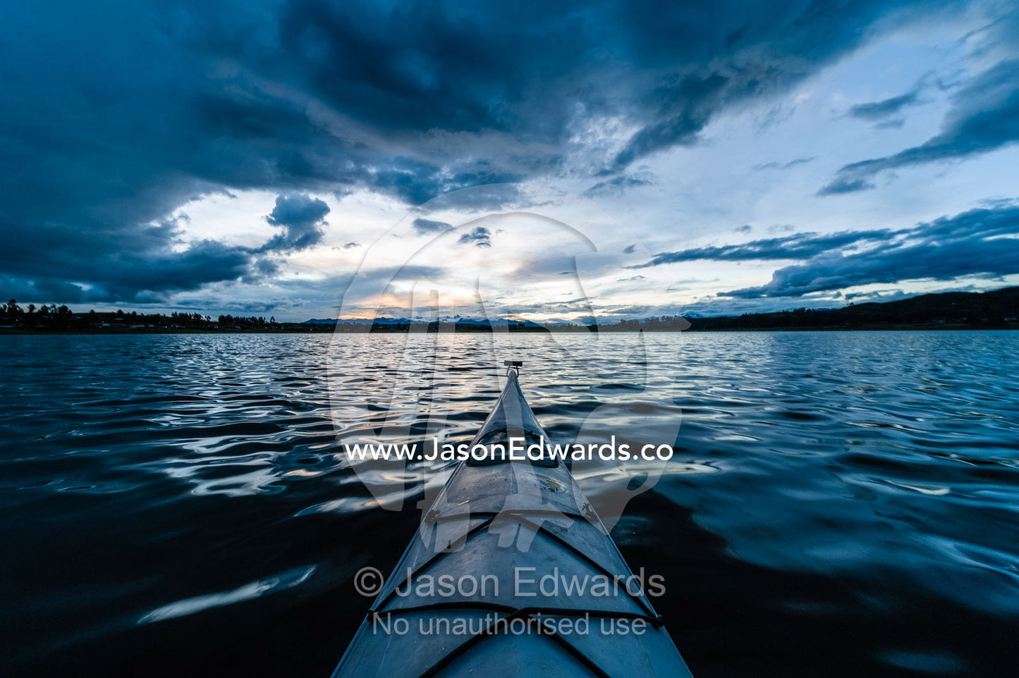 A canoe bow on a still lake in the Andes mountains beneath storm clouds. Peru.
