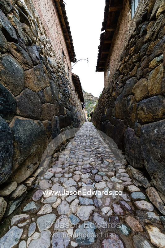 A village lane paved with stones and lined with high Inca dry-stone walls. Ollantaytambo, Peru.