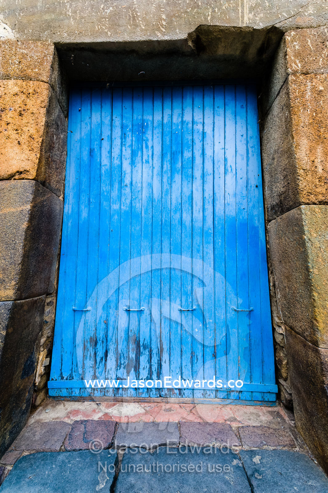 A blue wooden door in a Inca dry-stone archway Ollantaytambo, Peru.