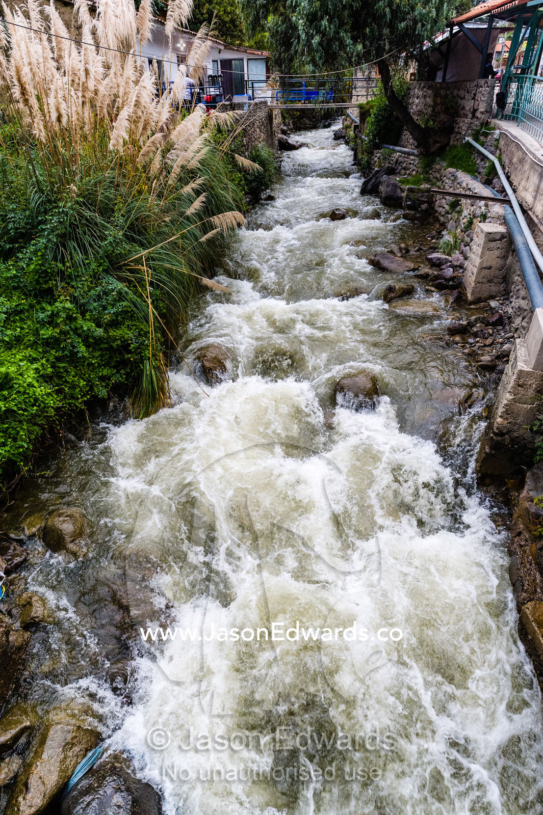 Run-off from the mountains creates river rapids in a canal in an Andes village. Ollantaytambo, Peru.