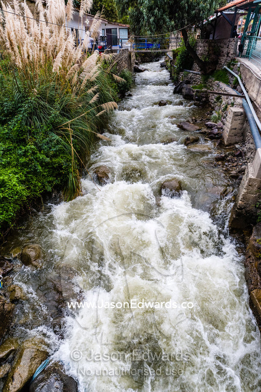Run-off from the mountains creates river rapids in a canal in an Andes village. Ollantaytambo, Peru.