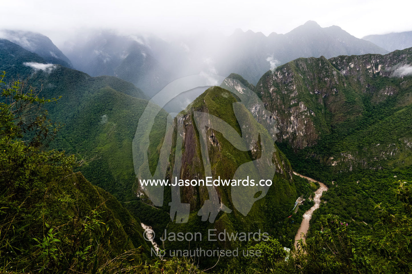 Sheer mountains covered in forest and jagged peaks above a winding river in the Andes. Peru.