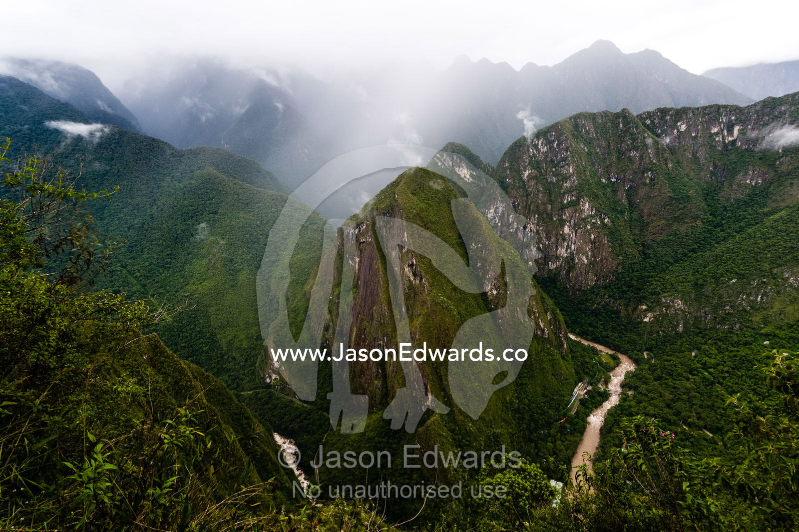 Sheer mountains covered in forest and jagged peaks above a winding river in the Andes. Peru.