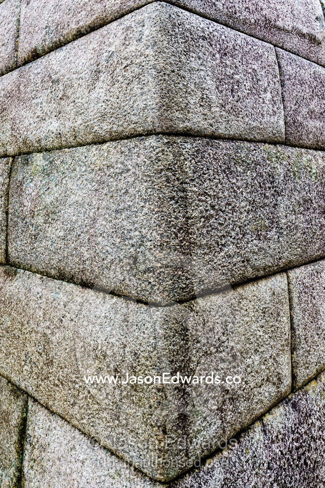 The linear textured corner of a Inca polished dry-stone wall at the Macchu Picchu ruins. Peru.