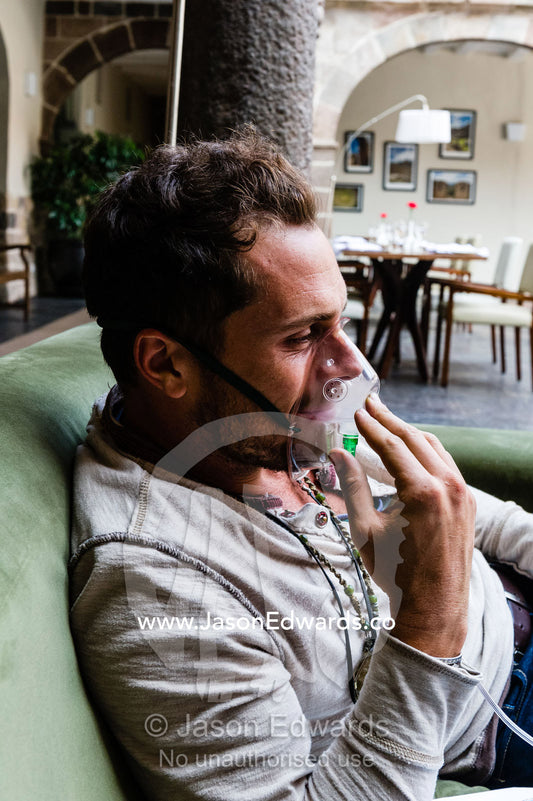 Tourists breathe in oxygen from a gas cylinder to acclimatise to the high altitude. Cusco, Peru.