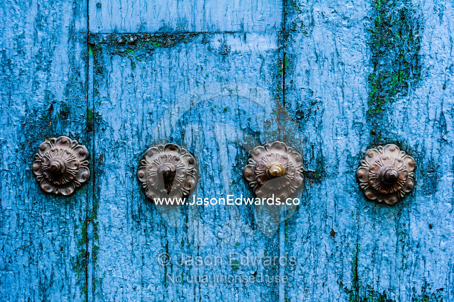 Steel studs in a weathered blue timber door in the Andes mountains. Cusco, Peru.