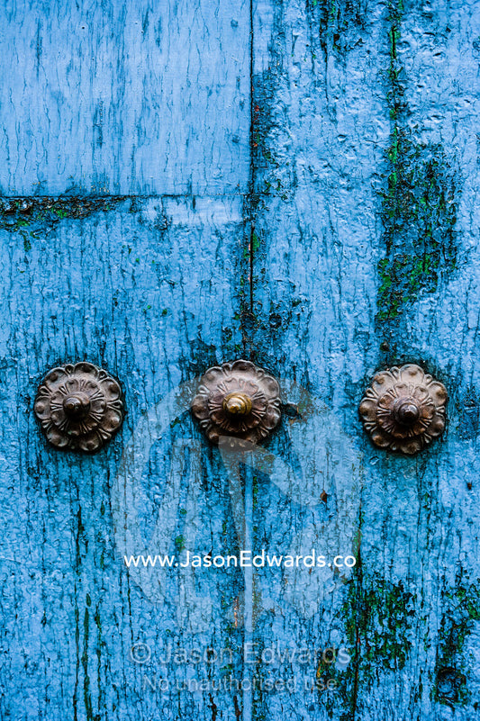 Steel studs in a weathered blue timber door in the Andes mountains. Cusco, Peru.