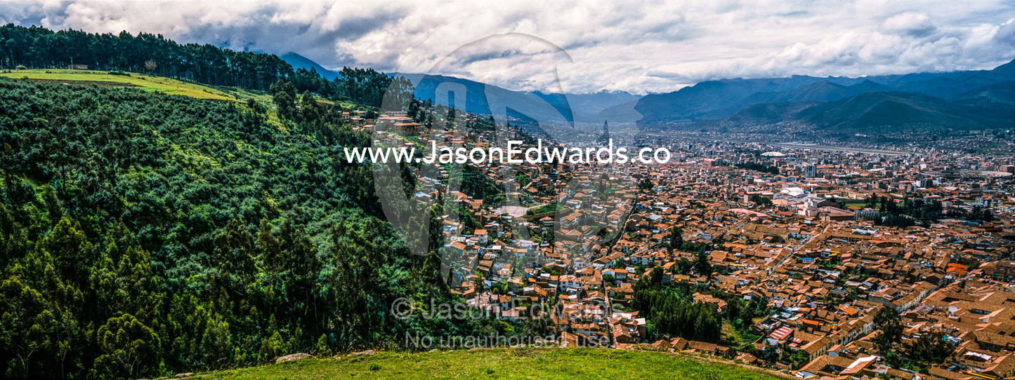 The city and suburbs of Cusco fill an Andes valley with terracotta roof tiles. Cusco, Peru.