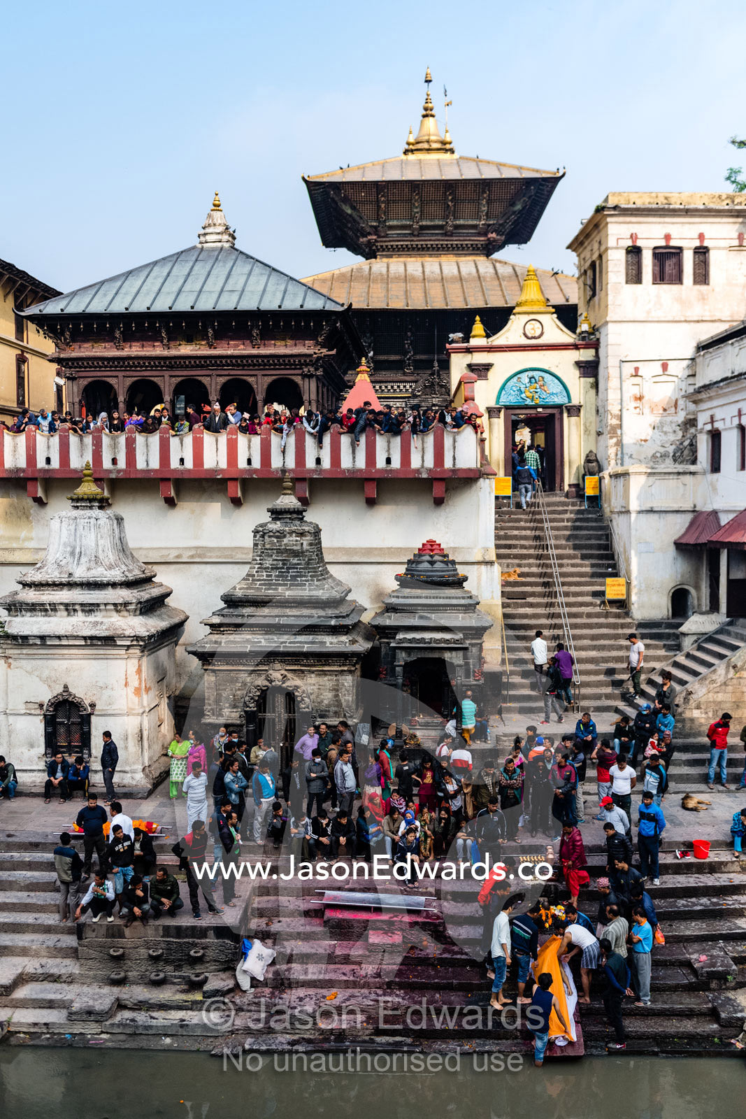 At a Hindu temple by a holy river family and friends gather to offer prayers and offerings to a family member during a cremation. Kathmandu, Pashupatinath Temple, Nepal