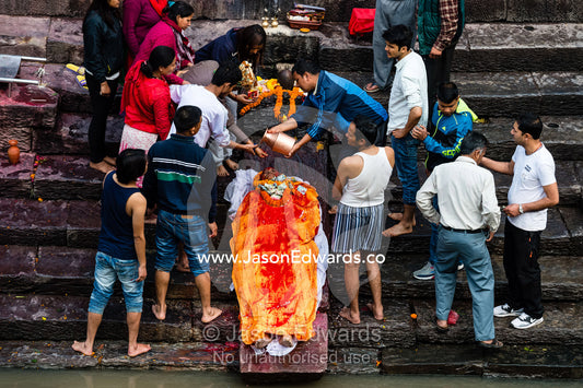 At a Hindu temple by a holy river family and friends gather to offer prayers and offerings to a family member during a cremation. Kathmandu, Pashupatinath Temple, Nepal