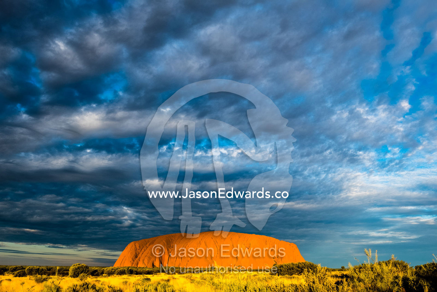 Clouds fill the vast desert sky over the ochre face of Uluru. Uluru-Kata Tjuta National Park, Northern Territory, Australia