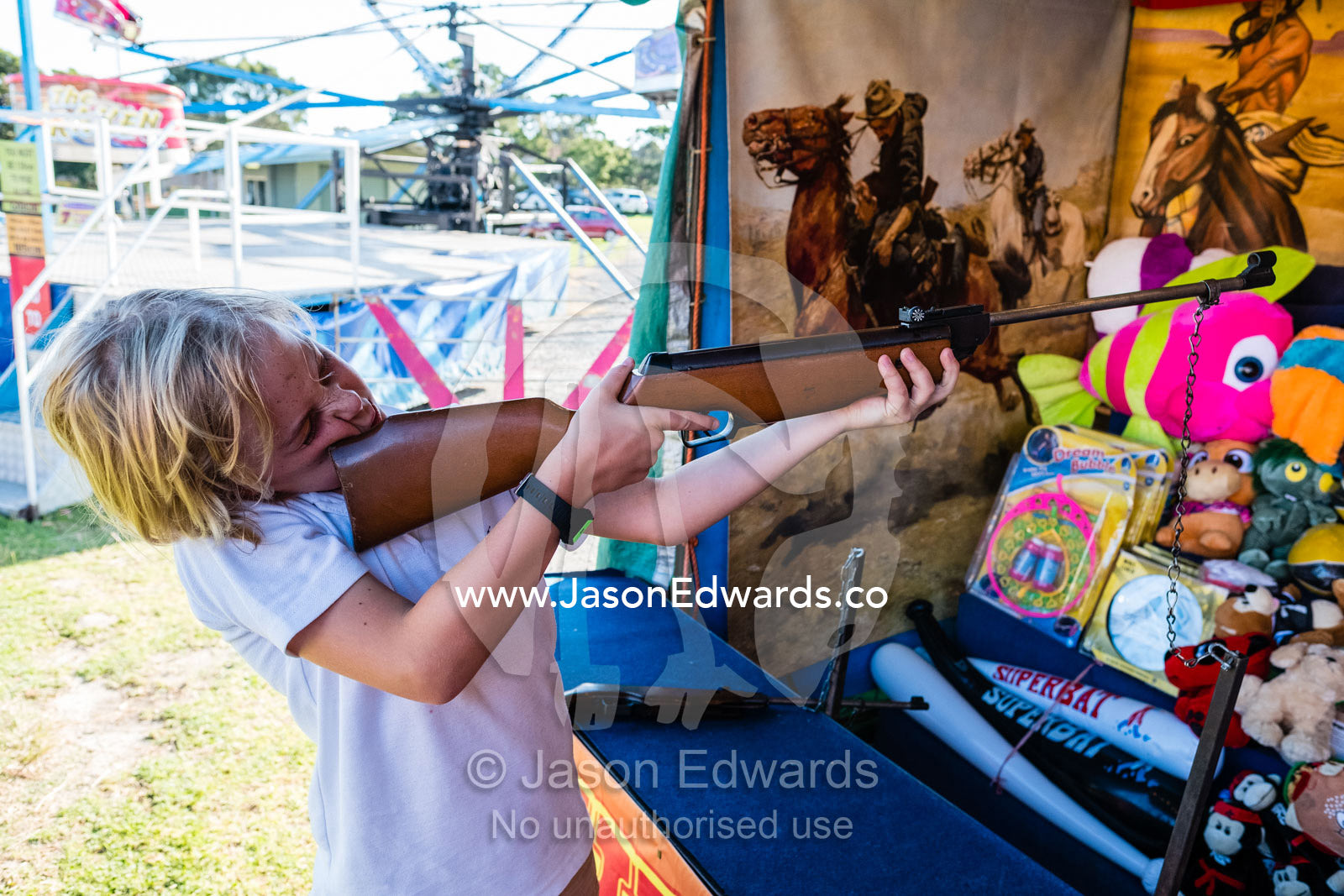 A boy shoots a gun at metal duck in a sideshow at a fair. Inverloch, Victoria, Australia