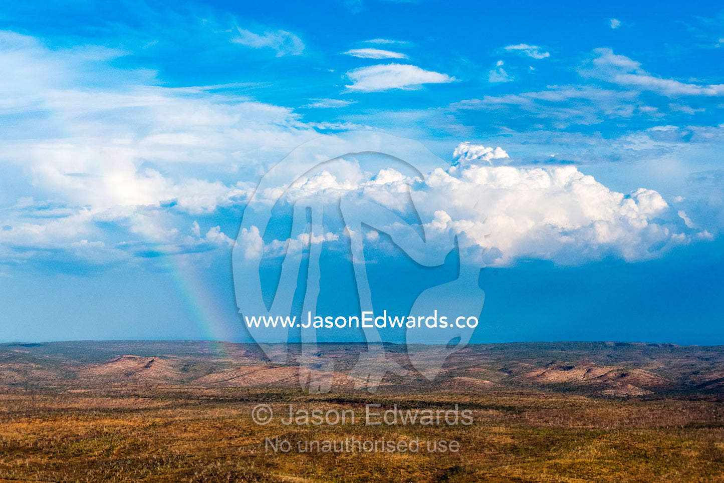An aerial view of a vast arid outback cattle station with scattered trees and rainbow. Timber Creek, Bullo River Station, Northern Territory, Australia