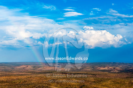 An aerial view of a vast arid outback cattle station with scattered trees and rainbow. Timber Creek, Bullo River Station, Northern Territory, Australia