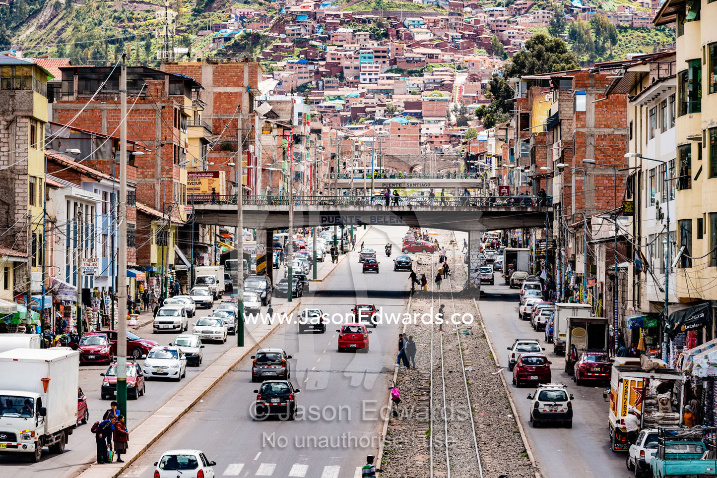 Traffic congestion and train lines running along a main road in an Andean city. Cusco, Cusco Region, Peru