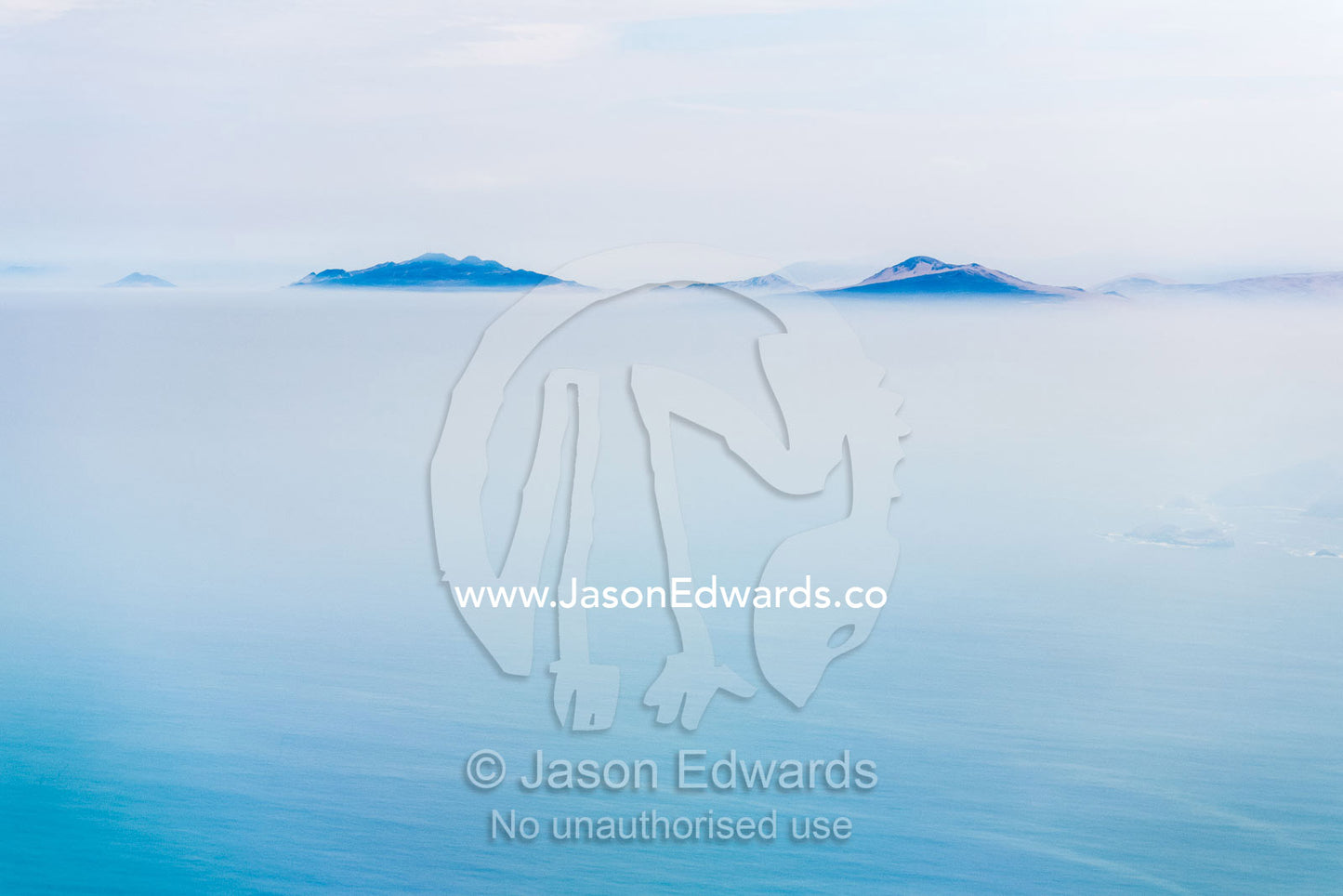 Mountains appear through a canopy of sea mist and fog on the coast. Lima, Peru