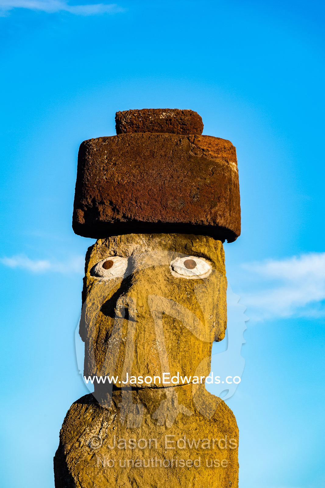 The human figure of a Moai statue wearing a topknot greets the dawn on the coast of Easter Island. Ahu Tahai, Rapa Nui, Easter Island, Chile