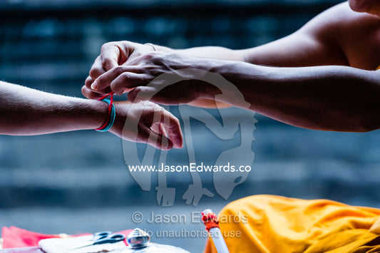 A Buddhist monk ties thin scarlet wool thread onto a tourist's left wrist. Siem Reap, Angkor Wat, Cambodia
