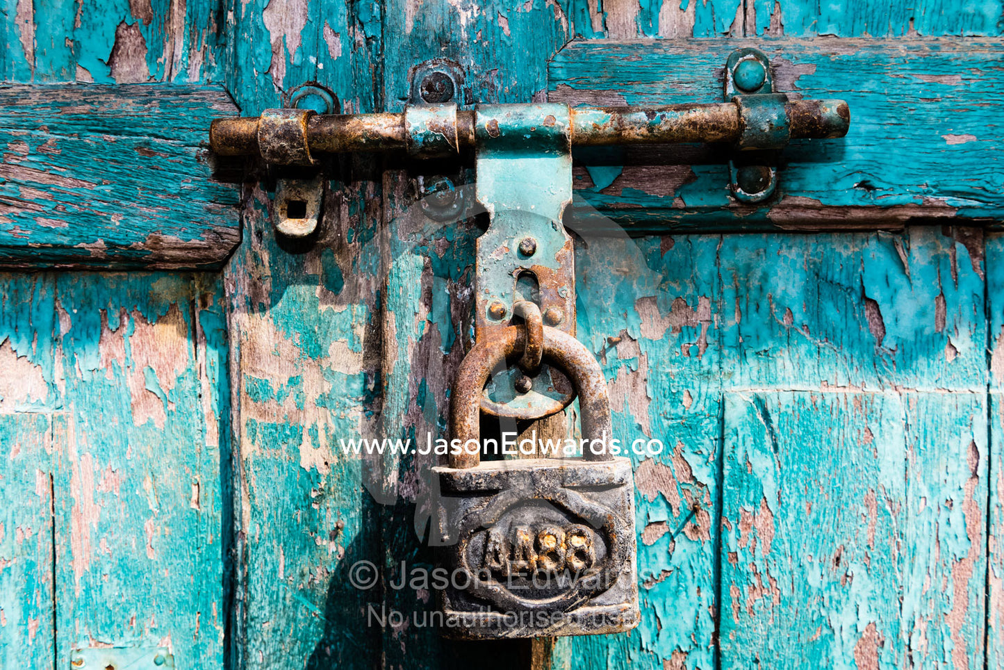 A rusting lock holds a latch and bolt on a door with blue peeling paint. Kathmandu, Bhaktapur, Nepal