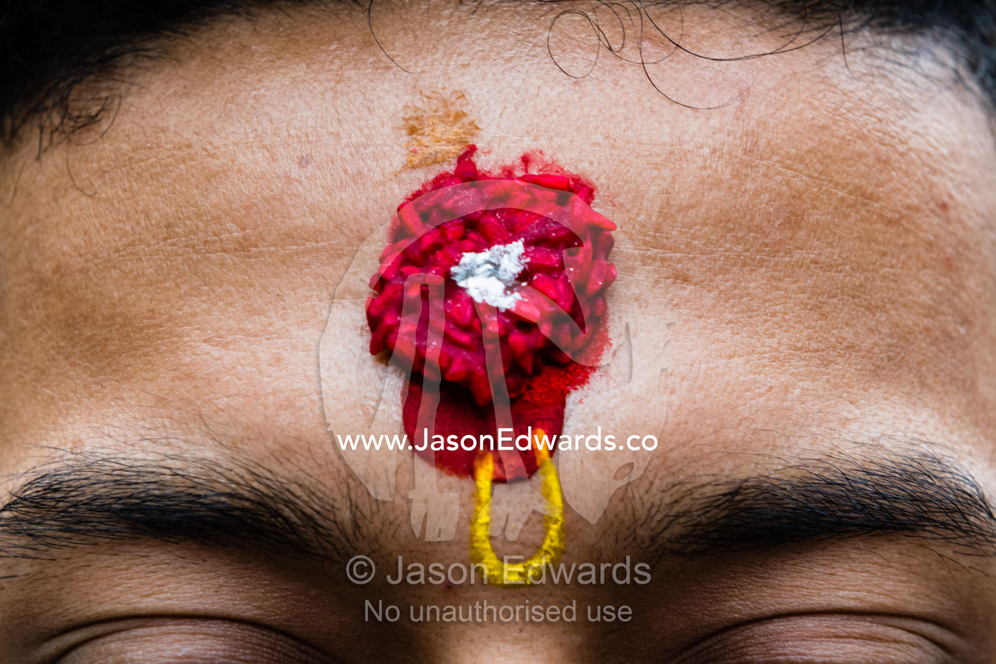 A tilaka, a forehead marking, of vermillion-colored rice. Kathmandu, Pashupatinath Temple, Nepal