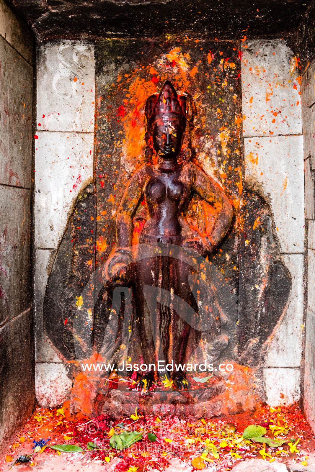 A stone icon of a Hindu goddess, probably Durga, encrusted with puja powder, known as kumkuma. Kathmandu, Pashupatinath Temple, Nepal