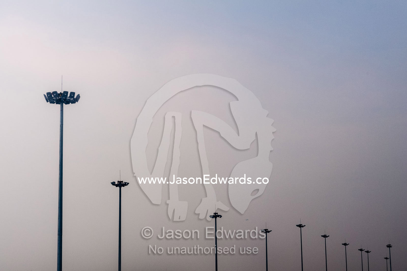 Tarmac lighting poles vanishing into the distance at a large airport shrouded in pollution. Chengdu, Sichuan Province, China