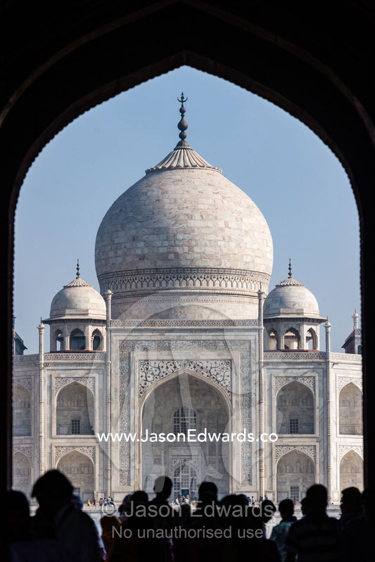 Tourists flock beneath an arched doorway to view the Taj Mahal. Agra, Taj Mahal, Uttar Pradesh, India