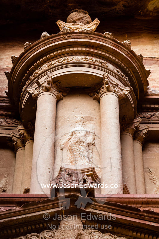 Detail of rock-cut facade of The Treasury tomb showing the circular tholos with eroded relief sculpture of the goddess Isis, Al-Uzza. Petra, The Lost City of Petra, Jordan
