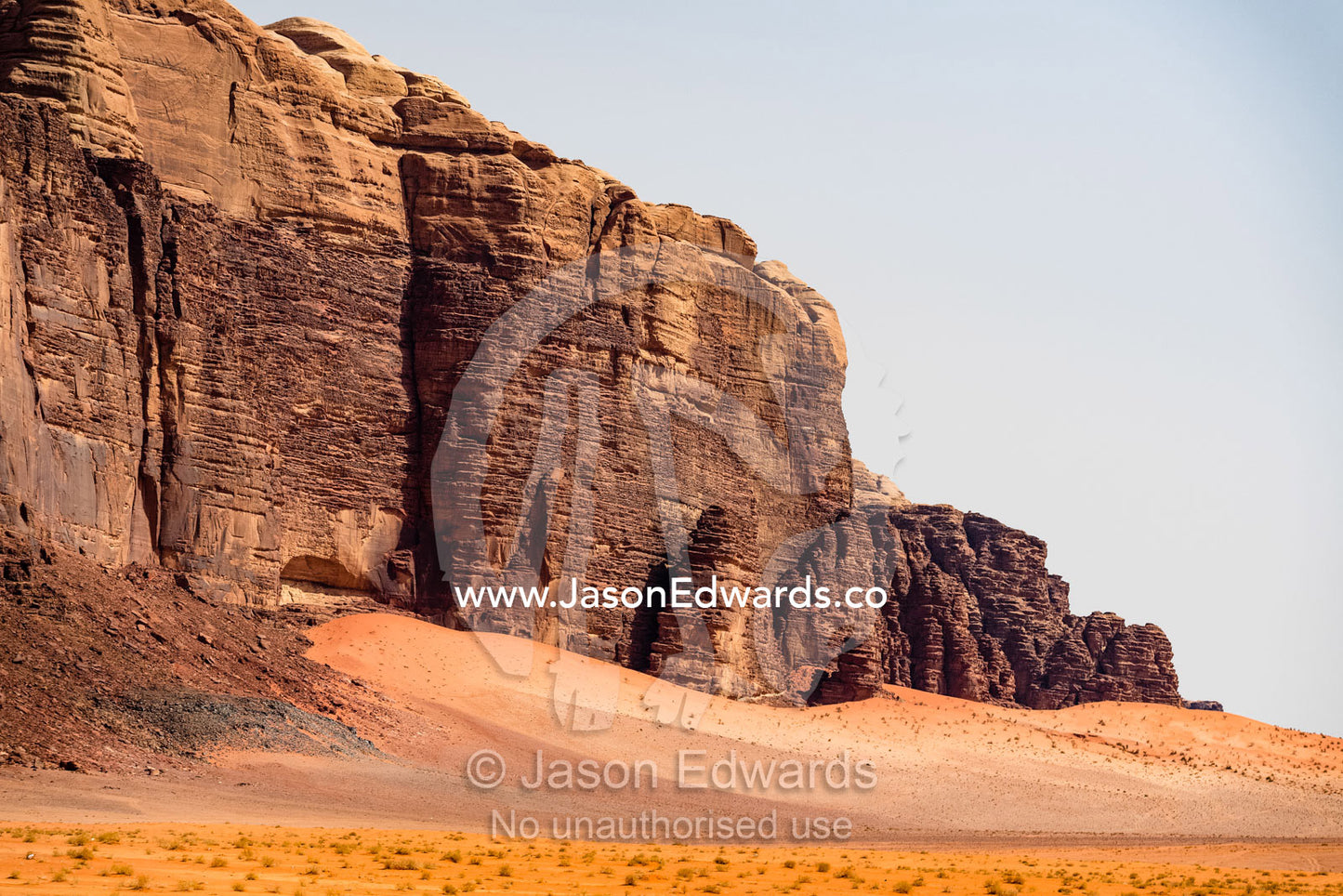 A sandstone escarpment rises from the sands in a desert wilderness. Wadi Rum, The Valley of the Moon, Jordan