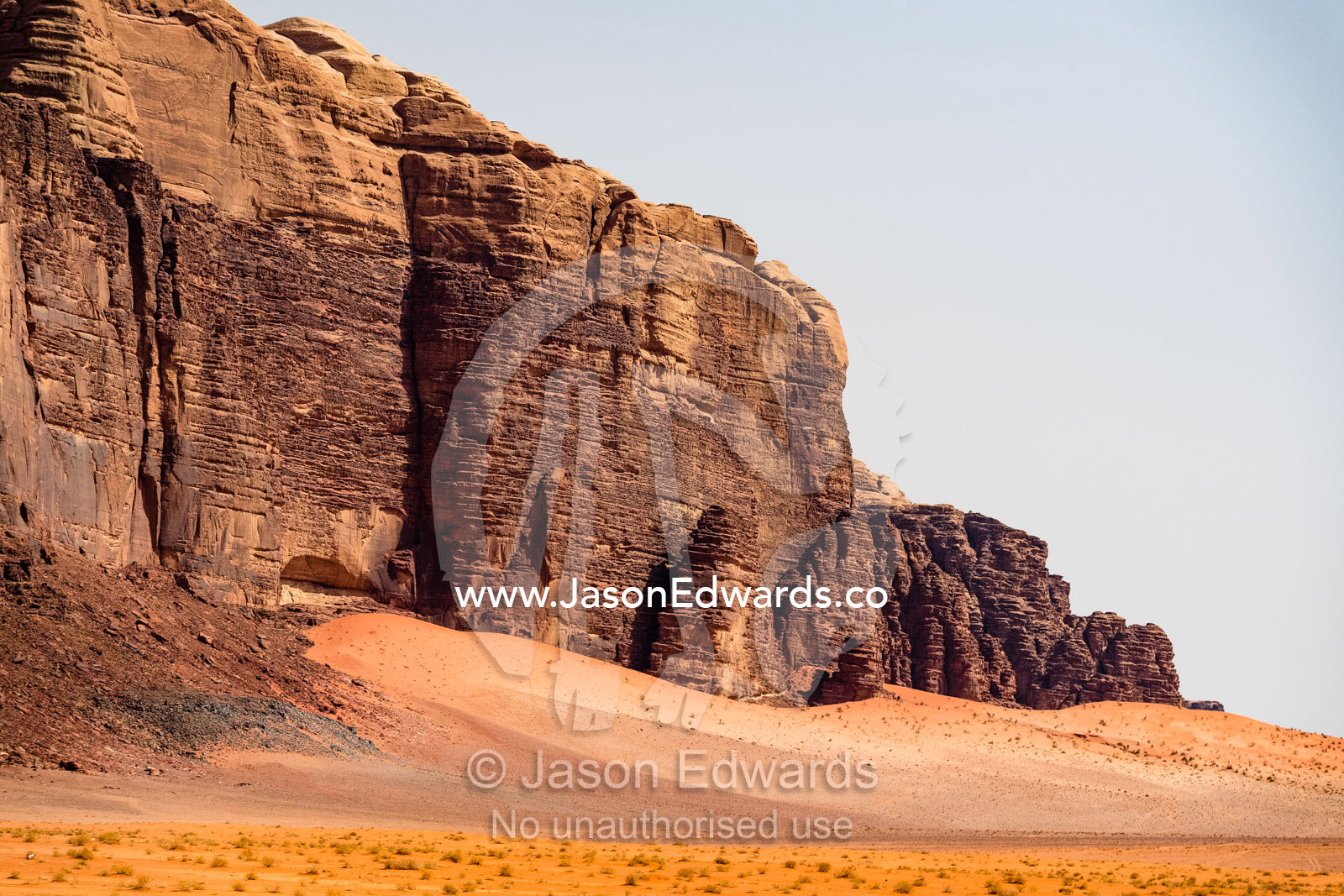 A sandstone escarpment rises from the sands in a desert wilderness. Wadi Rum, The Valley of the Moon, Jordan