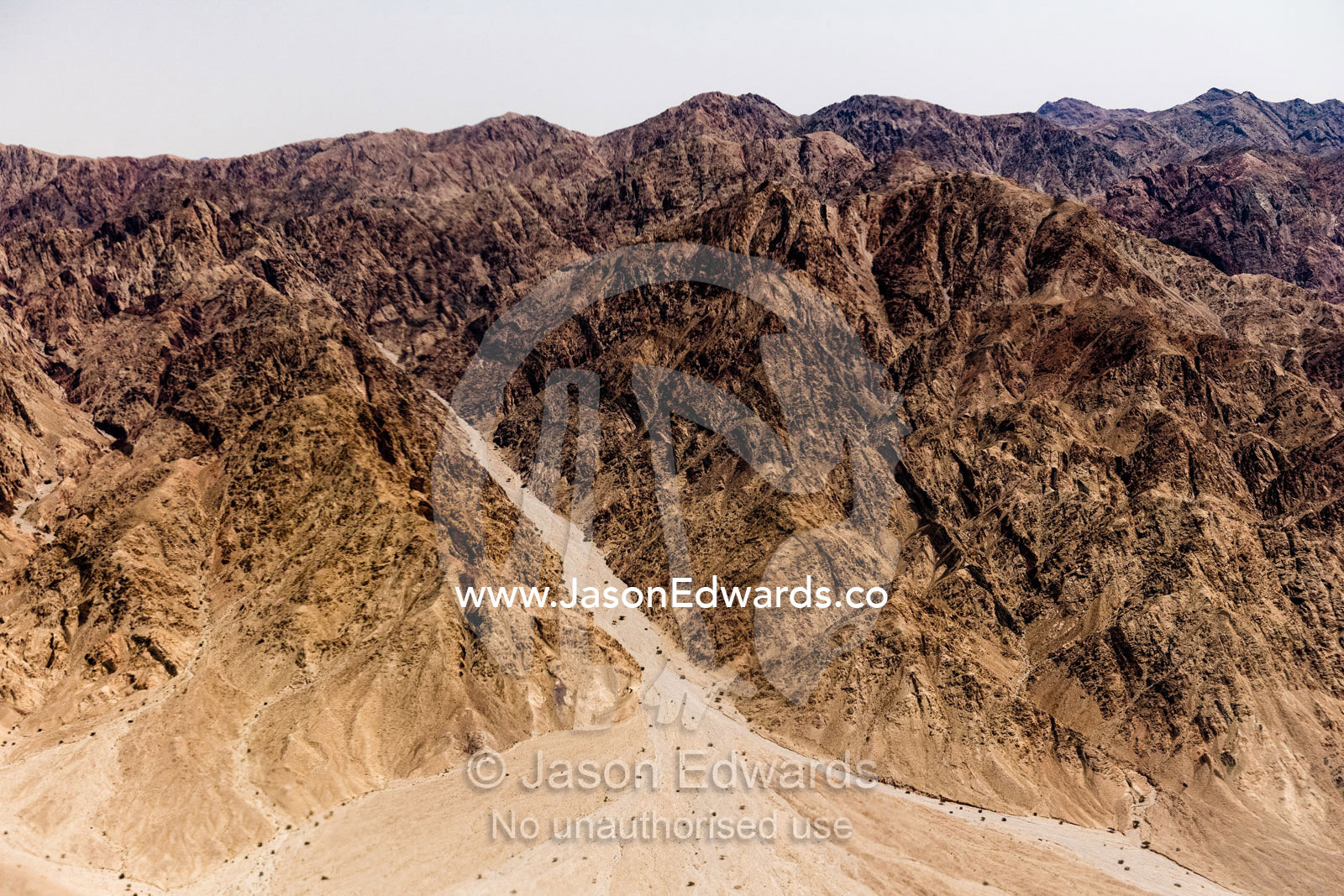 An aerial view of a sand river flowing out from desert mountains. Jordan