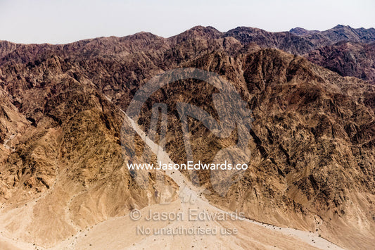 An aerial view of a sand river flowing out from desert mountains. Jordan