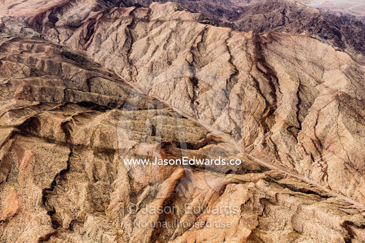 An aerial view of erosion carving into mountains in a desert valley. Jordan