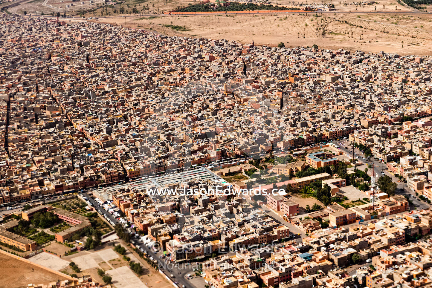 Crowded suburbs filled with apartment blocks and housing estates on a desert valley floor. Marrakech, Morocco