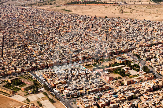 Crowded suburbs filled with apartment blocks and housing estates on a desert valley floor. Marrakech, Morocco