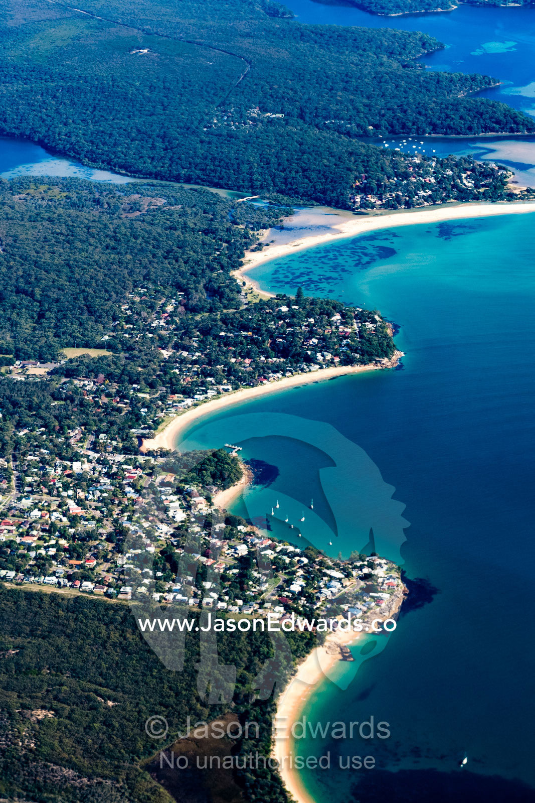An aerial view of houses crammed together in suburbs along a coastline. Sydney, New South Wales, Australia