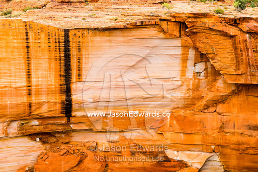 Sheer ochre sandstone cliffs drop into a remote desert gorge. Watarrka National Park, Northern Territory, Australia