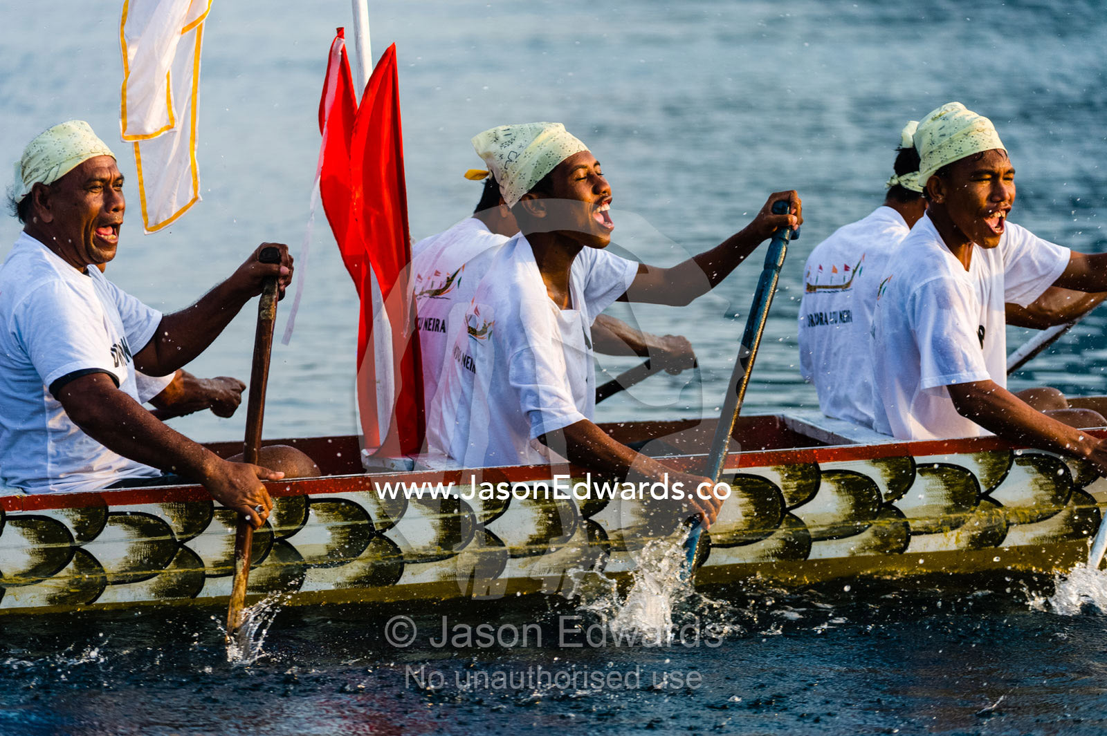 Villagers from a tropical island chanting songs as they paddle a war canoe. Banda Neira, Banda Islands, West Papua, Indonesia