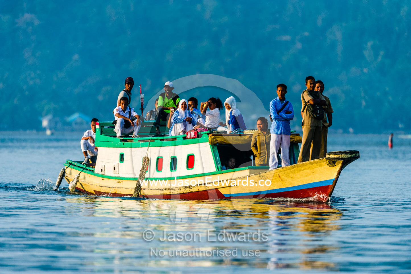 Police and villages travel between tropical islands on a water taxi. Banda Neira, Banda Islands, West Papua, Indonesia