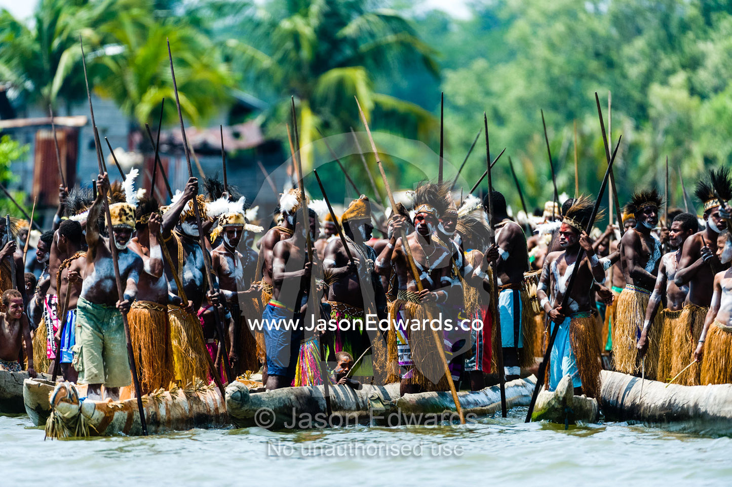 Asmat warriors chanting in war canoes during a Bis Pole raising ceremony in a village. Syuru Village, Asmat Regency, Papua, Indonesia