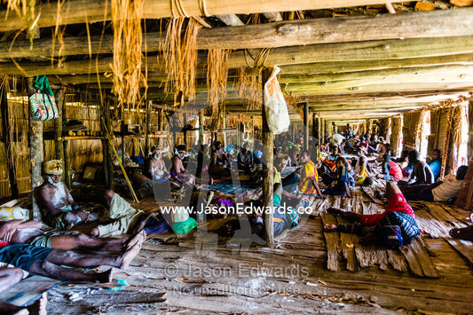 Families gather in a communal space to rest in a Longhouse during the heat of the day. Syuru Village, Asmat Regency, Papua, Indonesia
