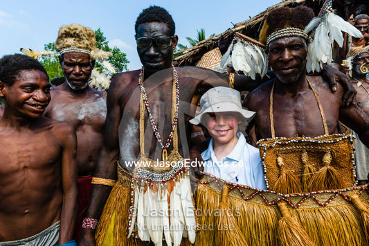 A western boy meets Asmat warriors in grass skirts during a tribal ceremony. Yahunyufri Village, Asmat Regency, Papua, Indonesia