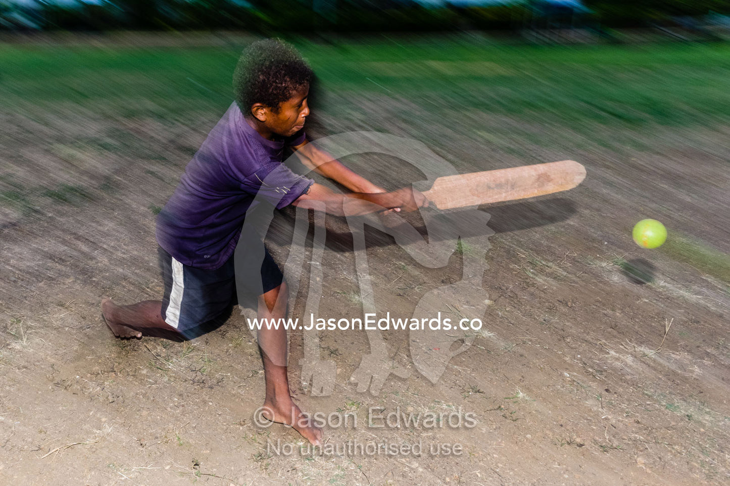 A boy playing cricket with a bat and ball on a remote tropical island. Samarai Island, Orangerie Bay, Milne Bay Province, Papua New Guinea